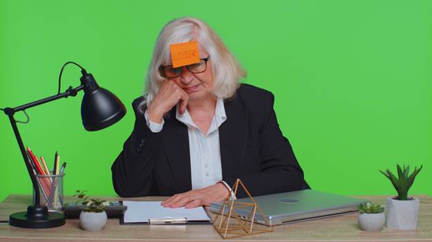 Older woman with sticky tab on forehead that says "Loser" - Age Discrimination